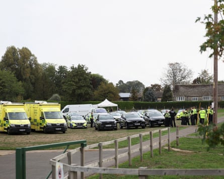 Ambulances and police cars parked on a village green.