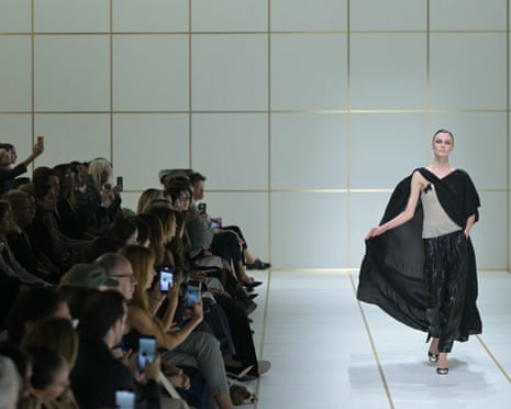 A model walks the Giorgio Armani runway in a flowing black cape.
