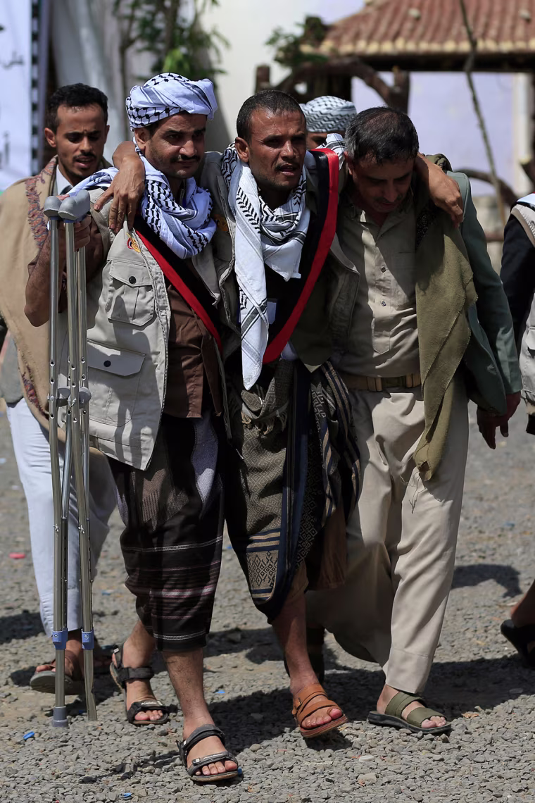 A man with an injured foot is assisted by two others.