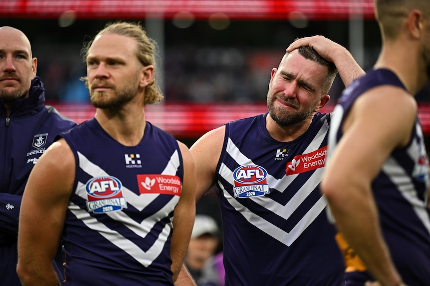 Two Fremantle players sad, one in tears after grand final
